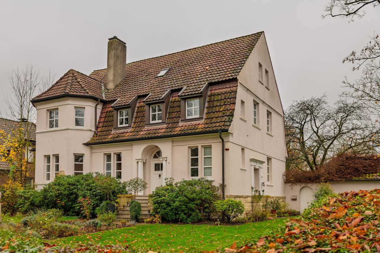 Services Elegant Tudor style house surrounded by autumn foliage, evoking a warm and cozy atmosphere.